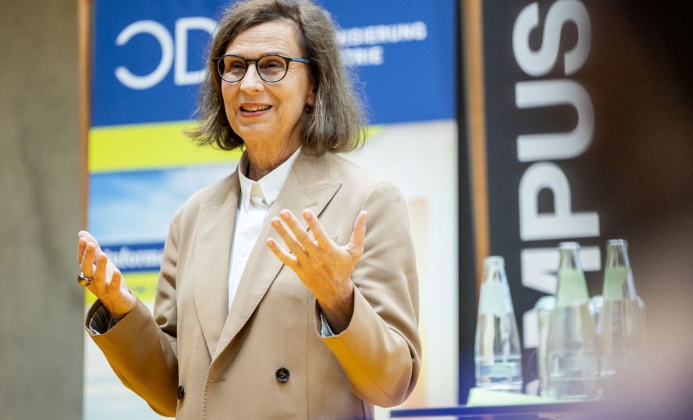 Frau stehend gestikuliert auf der Bühne