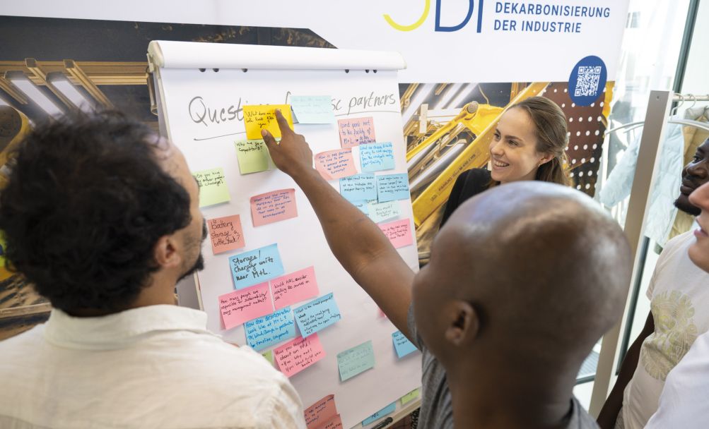 Studierende stehen vor Whiteboard und diskutieren Ideen