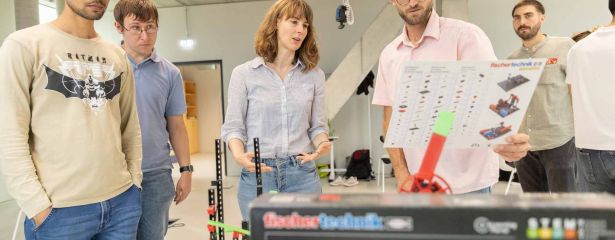 Studierende stehen nebeneinander und besprechen ein Projekt