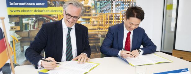 2 Personen unterzeichnend sitzend nebeneinander ein Papier