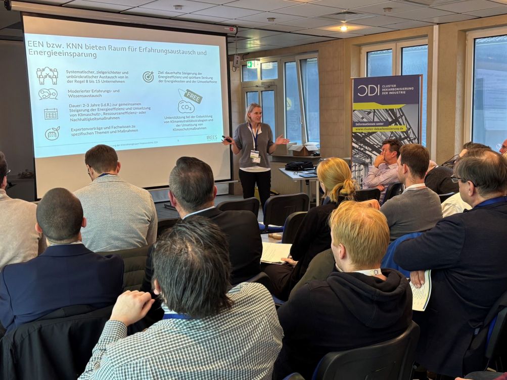 Person hlt einen Vortrag vor Publikum mit CDI und KEI Roll-Up im Hintergrund