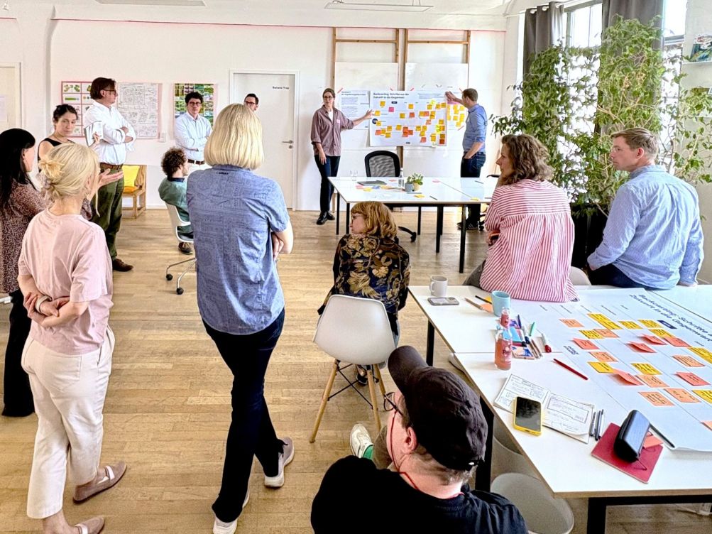 Person hält einen Vortrag vor Publikum mit CDI und KEI Roll-Up im Hintergrund