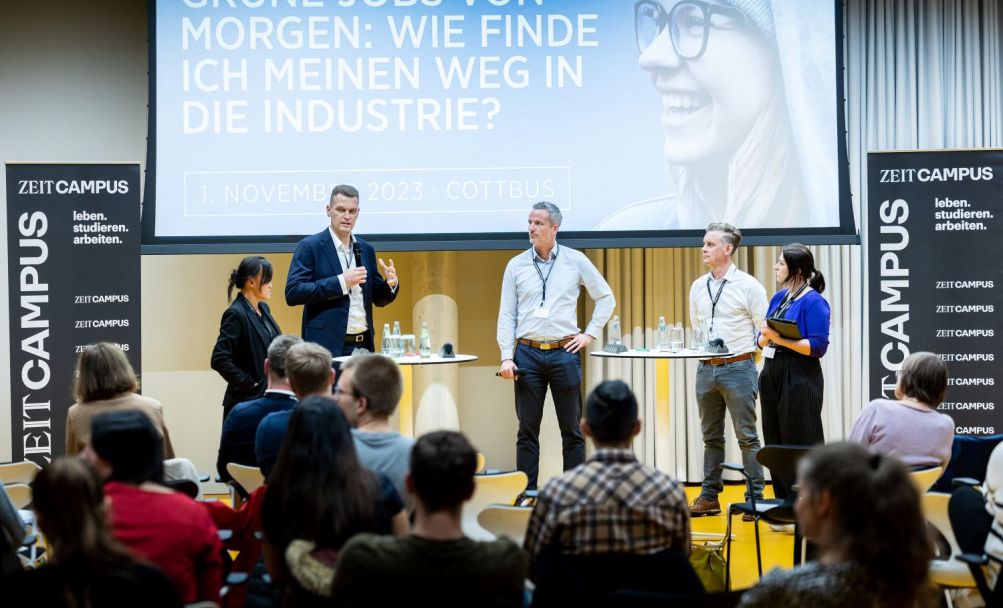 Fünf Personen stehen nebeneinander auf der Bühne und führen eine Diskussion