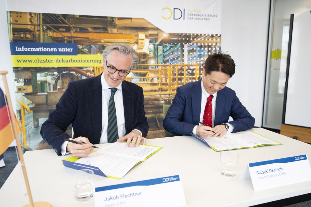 2 Personen unterzeichnend sitzend nebeneinander ein Papier