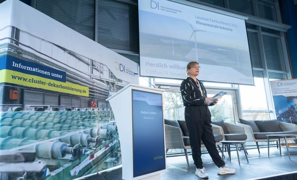 Frau stehend auf einer Bühne vor hängender Leinwand