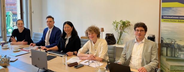 Personen sitzen nebeneinander an einem langen Tisch