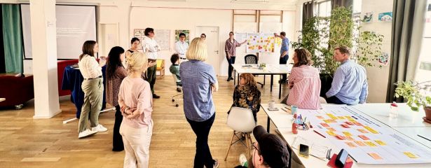 Menschen in Workshopumgebung stehen vor einem Whiteboard