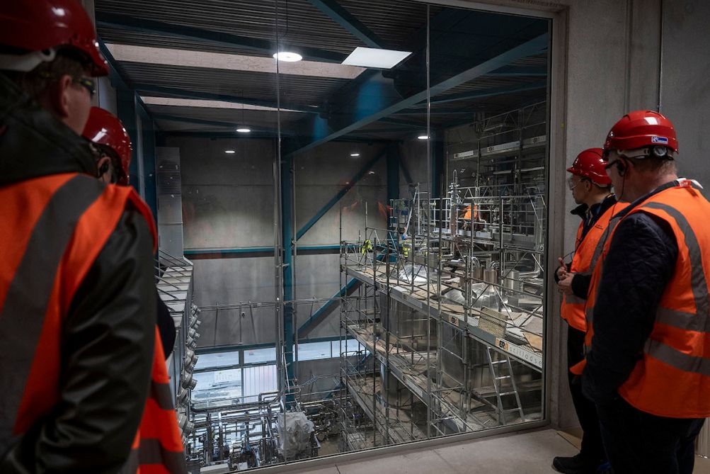 Menschen mit Bauhelmen schauen etwas an